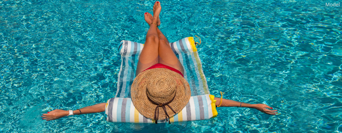 A woman long legs relaxing on a floatie in a beautiful pool (model)