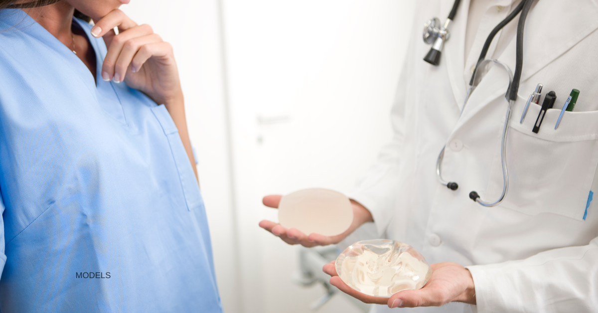 (MODELS) Doctor consulting with patient, holding different types of breast implants.