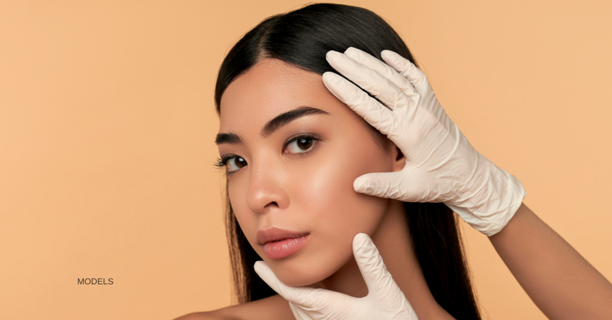 Woman (model) having her face held by gloved hands.