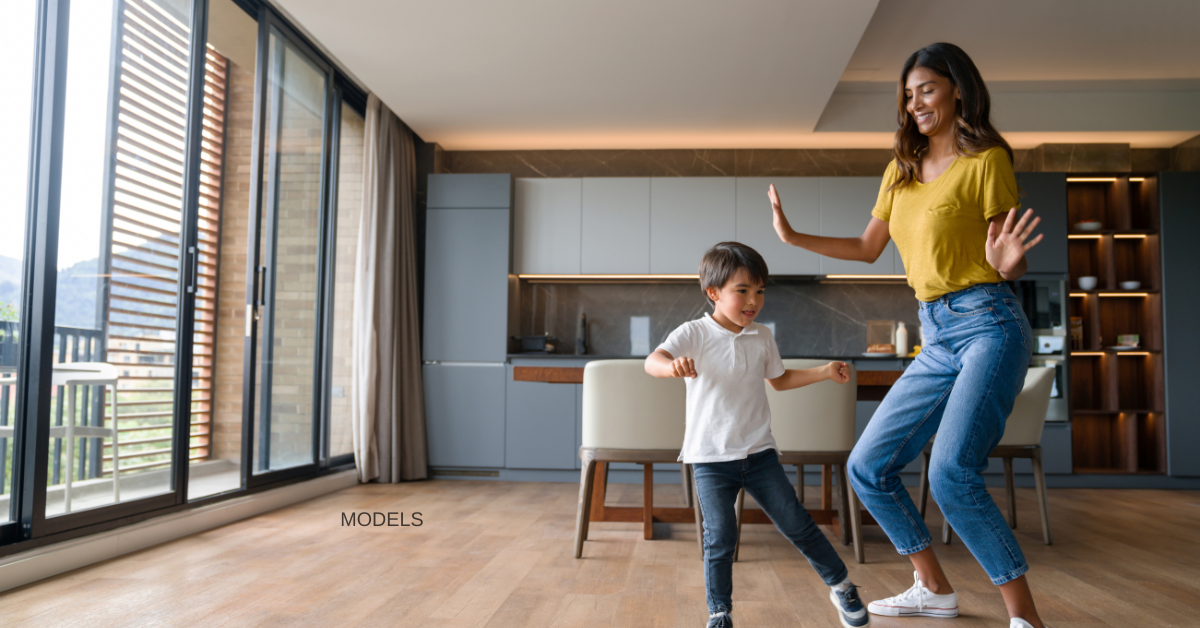 Woman and her son (models) dance together in the kitchen